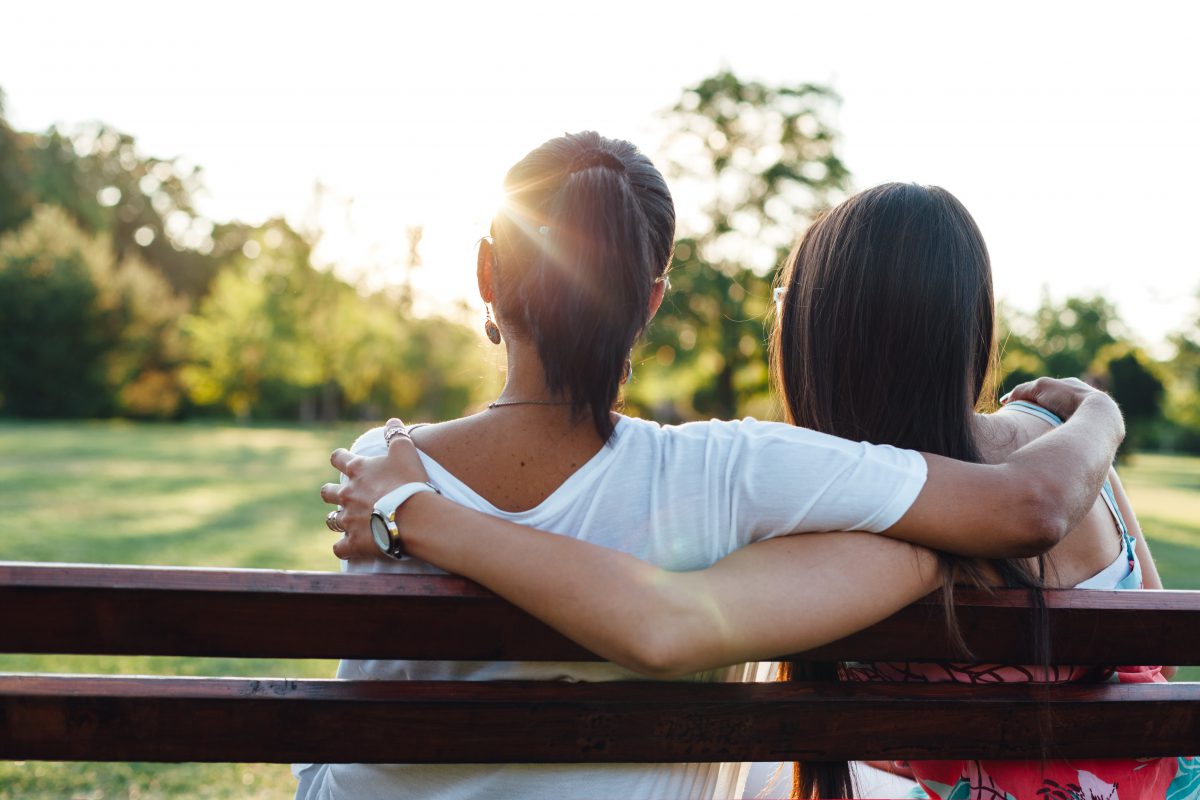 Photo of two women hugging on bench