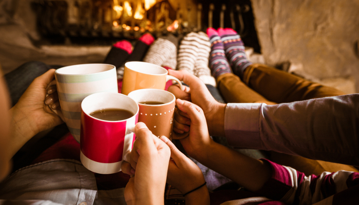 image of a group of hands holding christmas mugs representing holiday gathering