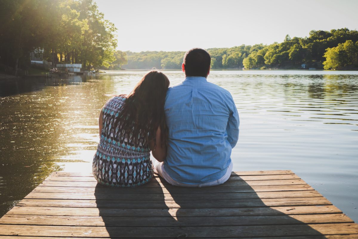 image of a man and woman sitting beside each other at the edge of a dock