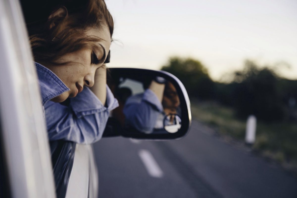 image of a young woman looking upset out of a car's passenger window