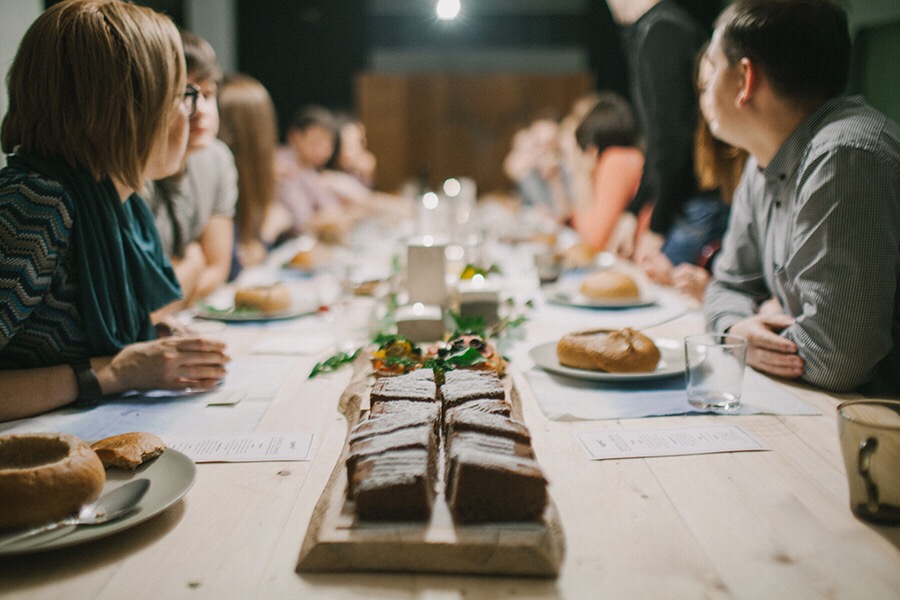 image of a long dinner table filled with people and plates of food representing intuitive eating
