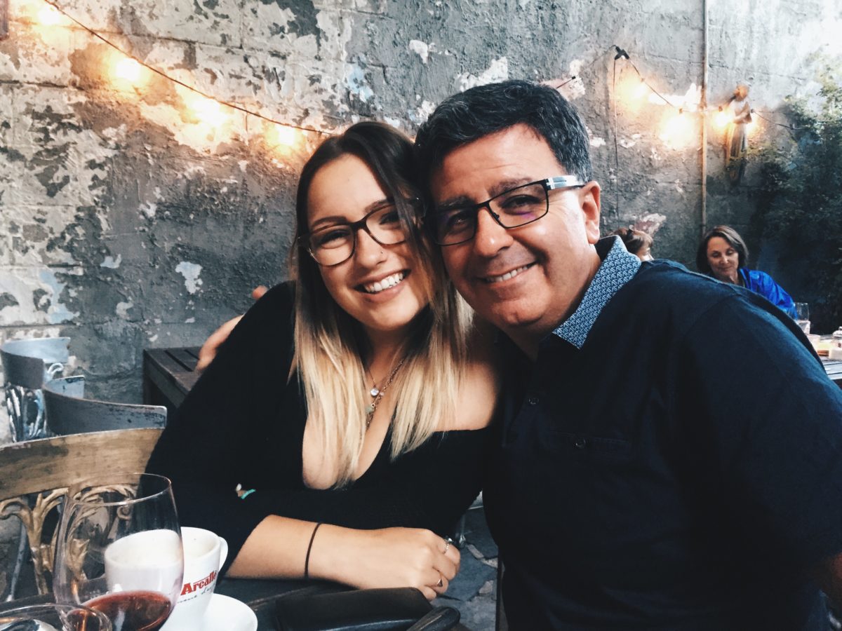 A father and daughter smiling for the camera inside a shop