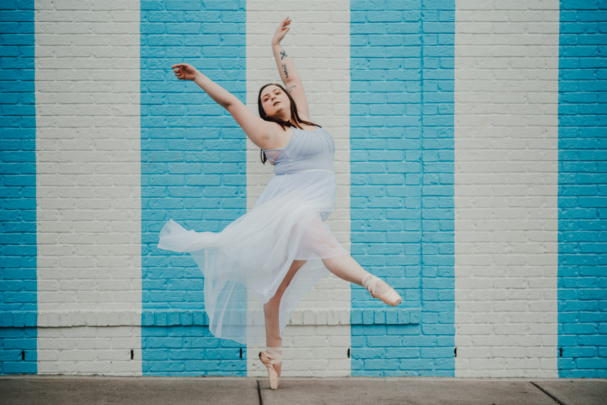image of a ballerina dancing in front of a white and blue striped wall