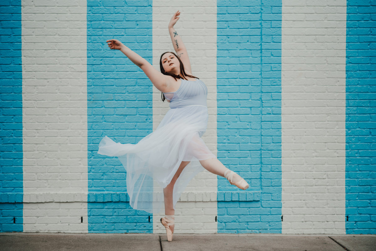 image of a ballerina dancing in front of a white and blue striped wall