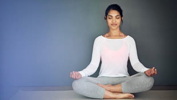 image of a young woman meditating against a blue wall