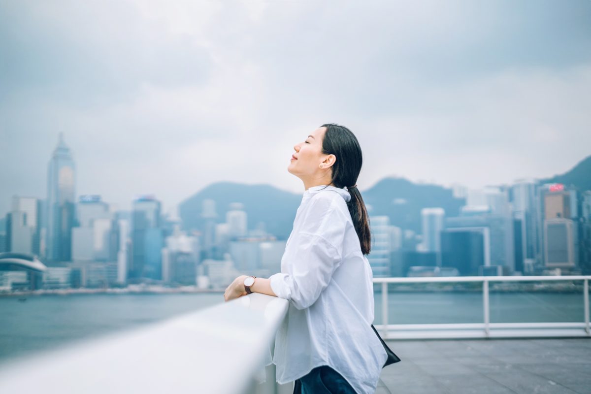 image of a young woman smiling with a large city backdrop behind her