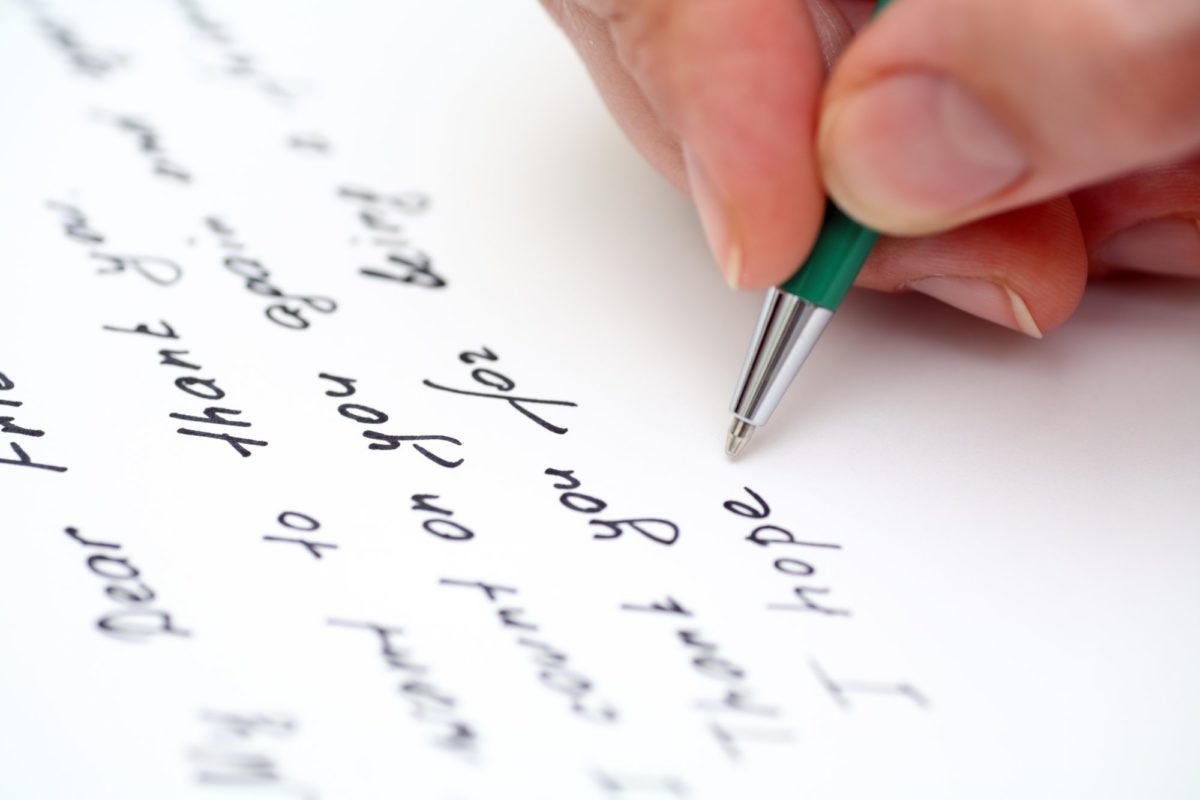 image of a hand writing a thank you note