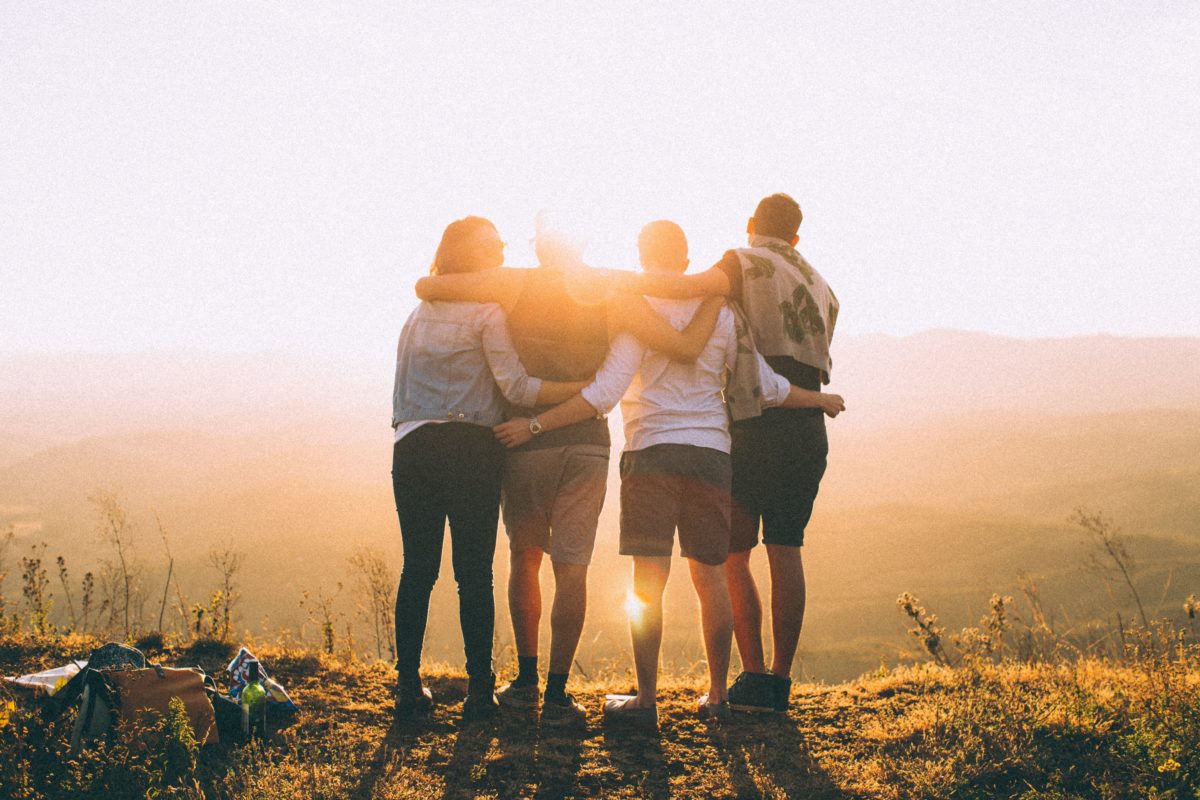 image of four young adults embracing at the top of a hill