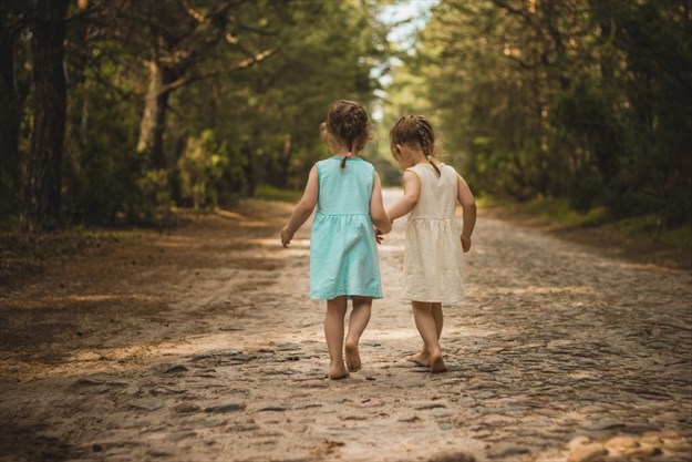 image of two young girls walking barefoot down a dirt road