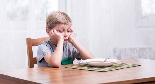 image of a boy looking disappointed at his bowl of food