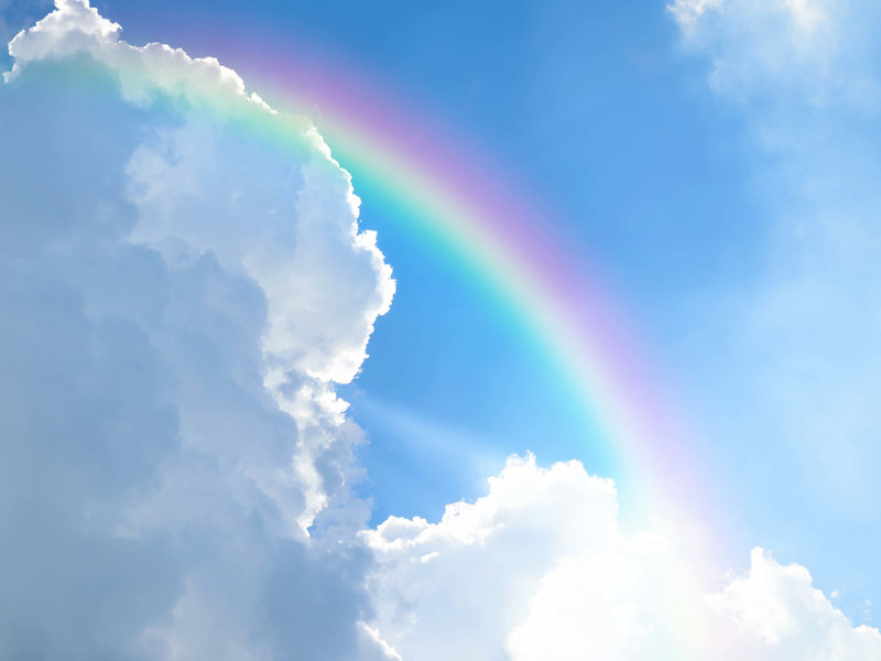 rainbow in blue sky with white clouds