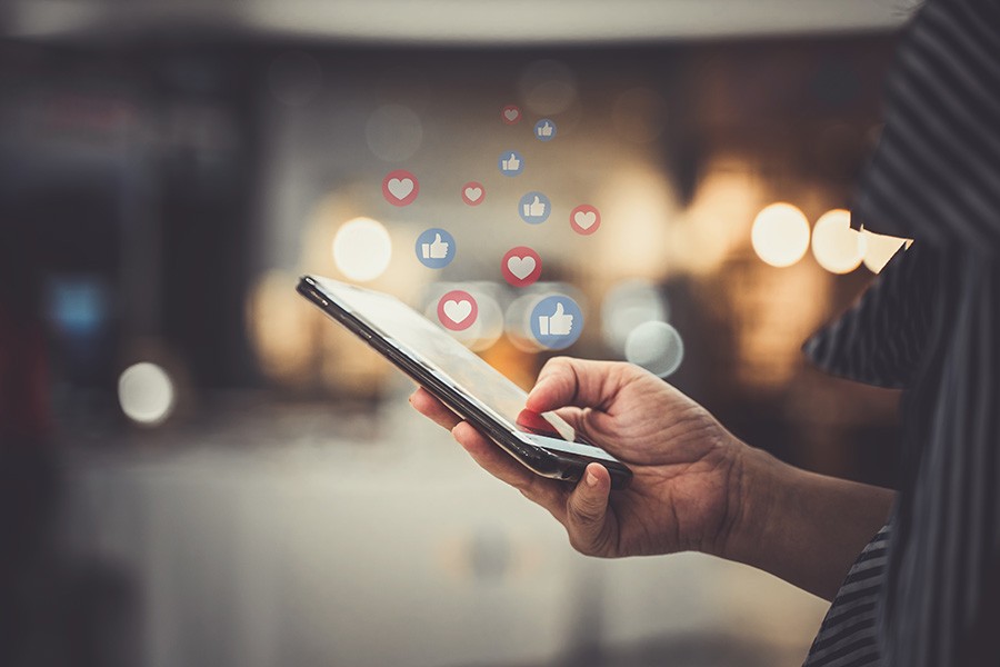 person scrolling on cell phone with social media icons in background