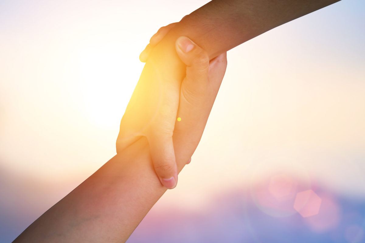 Two hands holding in front of sun