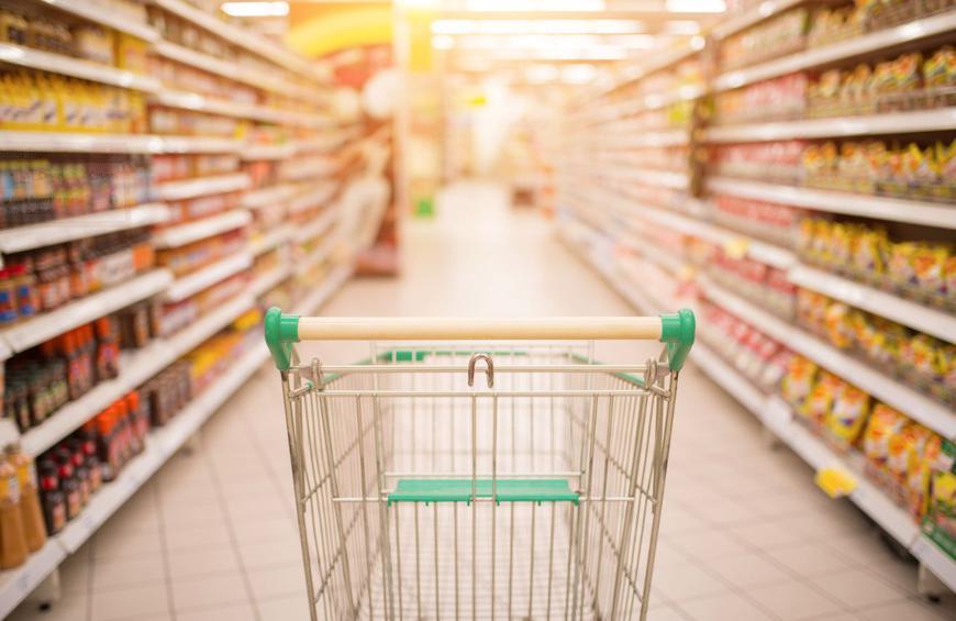 empty grocery cart in the middle of store aisle