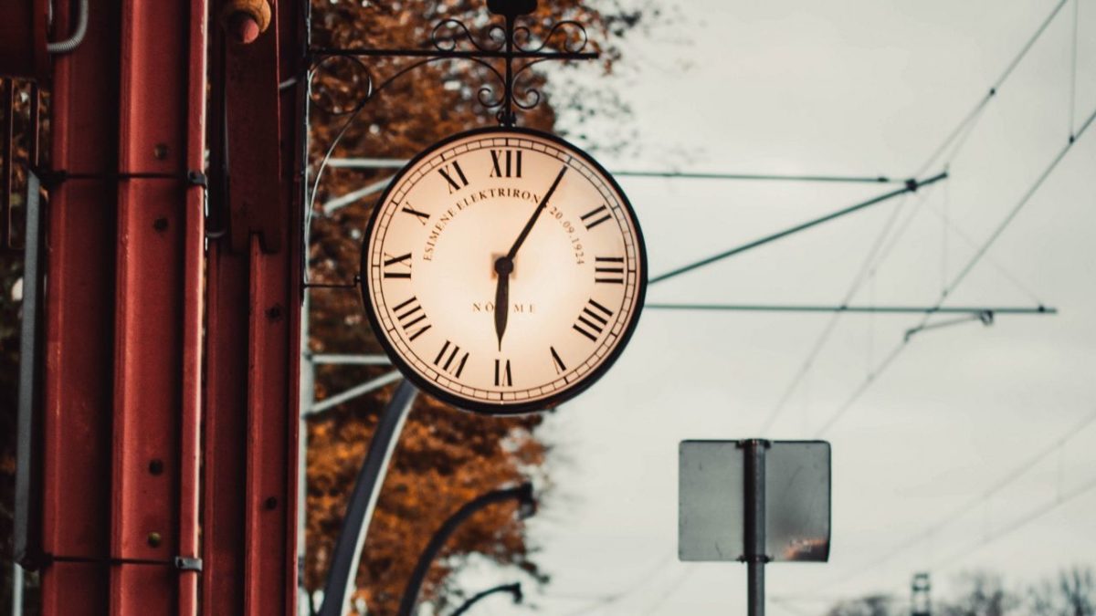 analog clock, reading 6:05, hanging outside