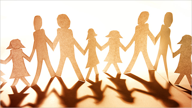 paper cutout of different size people holding hands on sepia background
