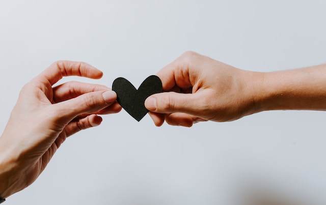 two people holding a paper heart