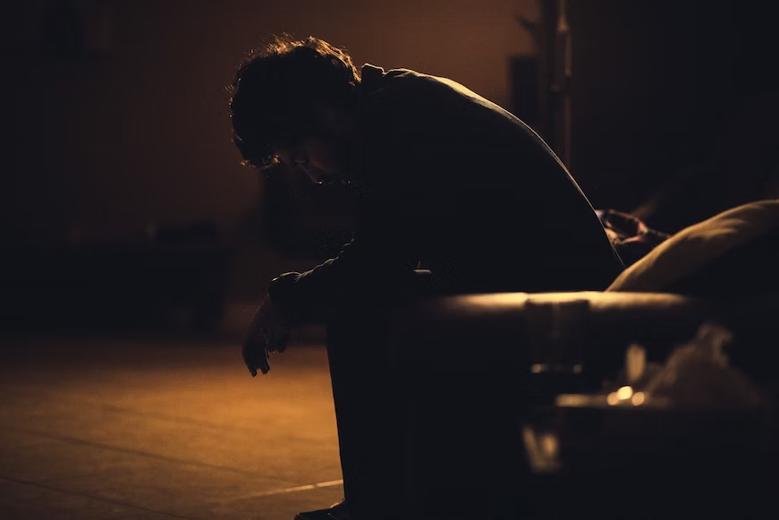 man looking distressed on a park bench at night