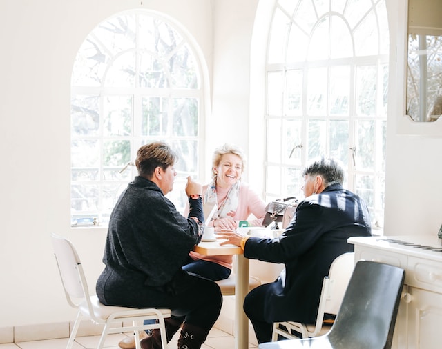 three friends sitting around a table in a breakfast nook