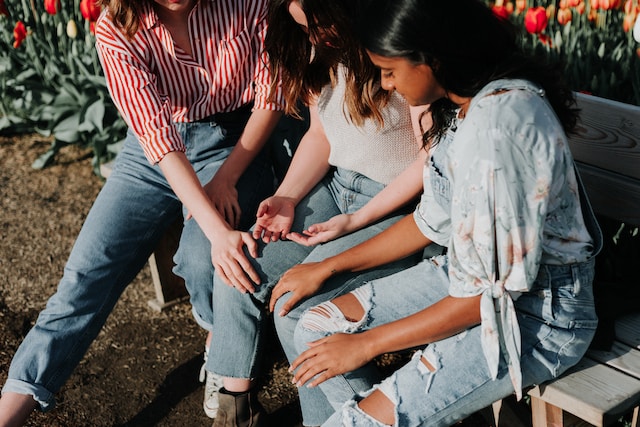 three friends sitting down on a bench