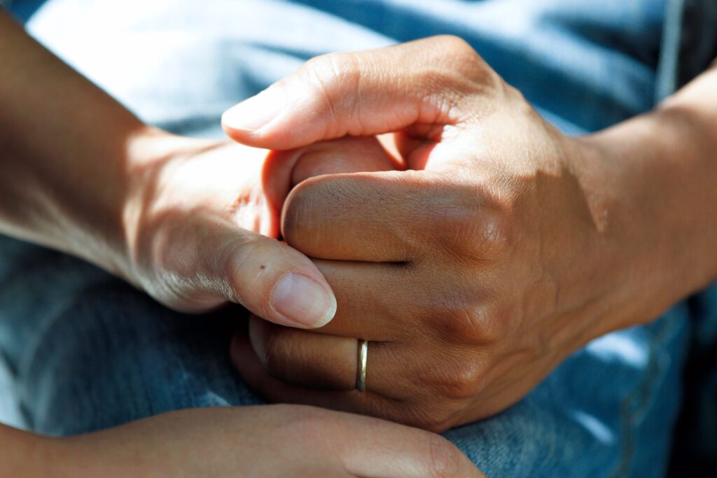 two people holding hands, one person is wearing a gold ring