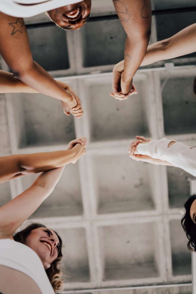 shot from below, three people holding hands looking at each other happily