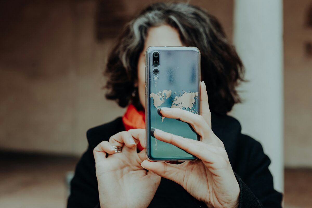 woman taking a selfie with her phone in a mirror, but her face is blocked by the phone