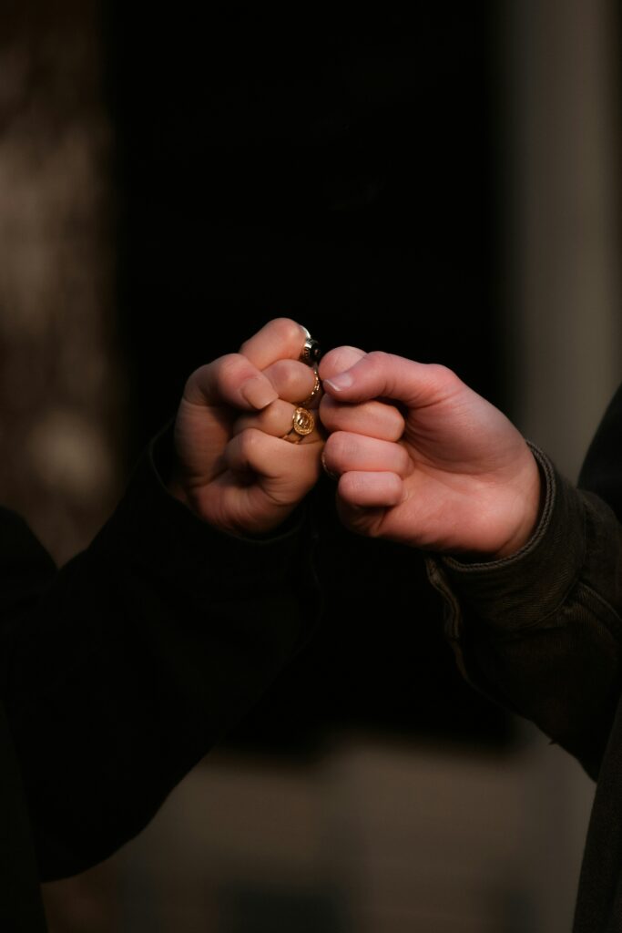 two people fist bumping in a dark room, only their hands are visible