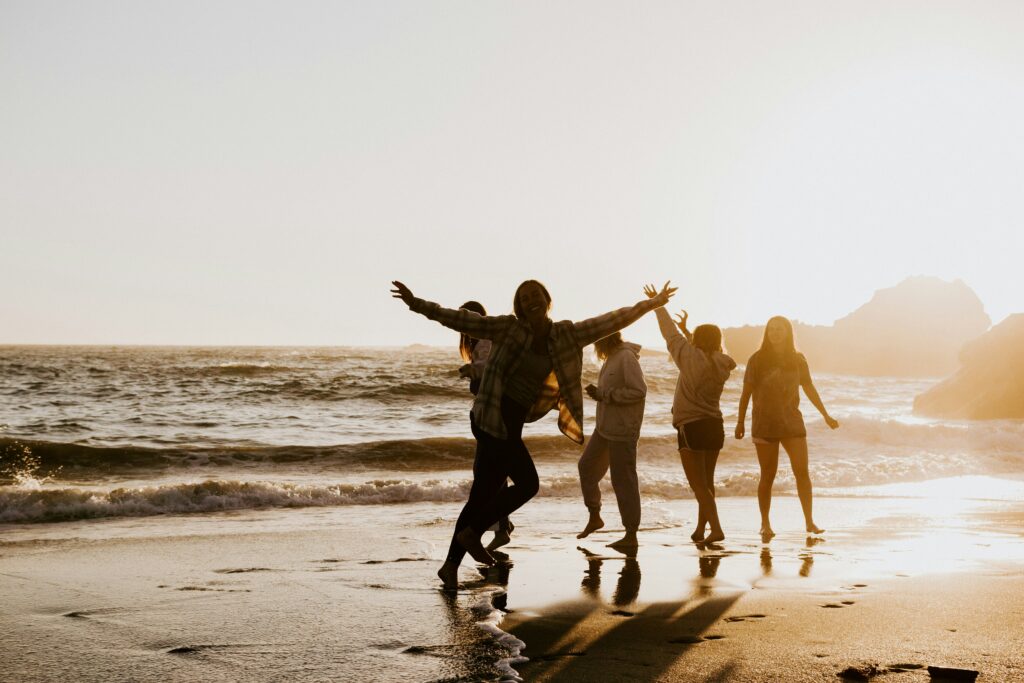 People dancing on a beach in golden hour.