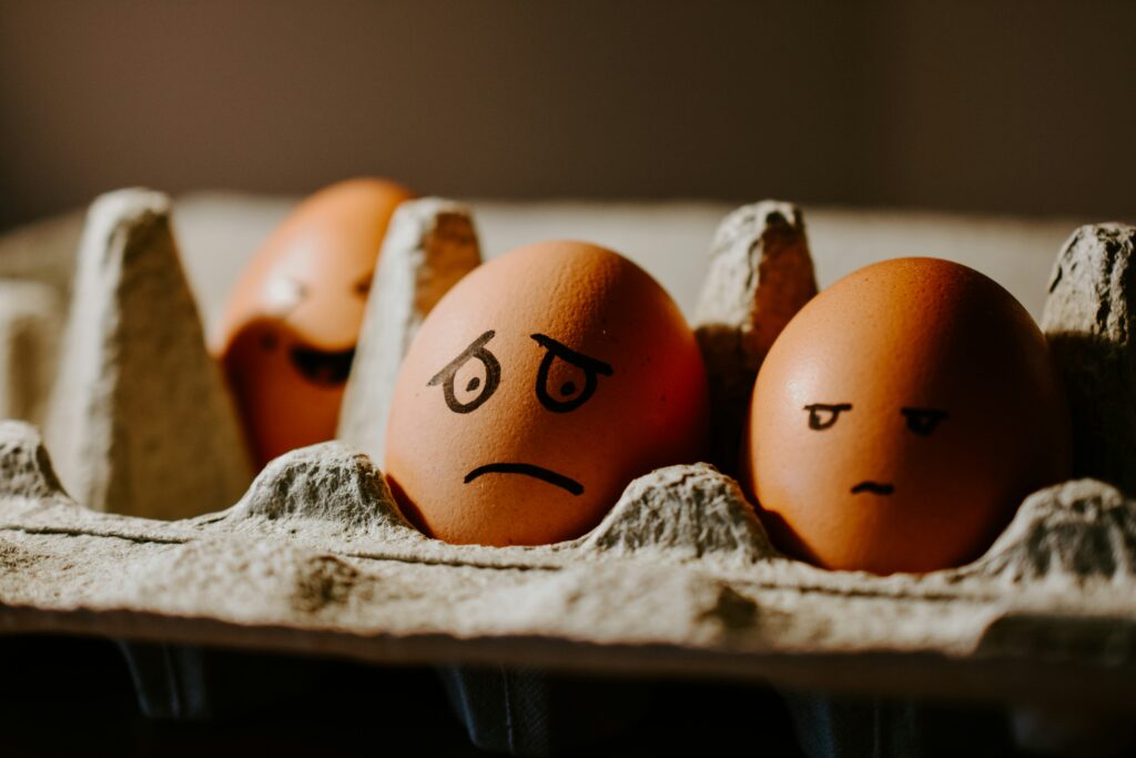 Eggs in an egg carton with faces drawn on them.