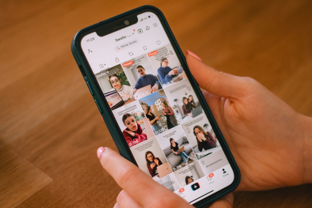 Hand scrolling through a TikTok feed on a smartphone.”