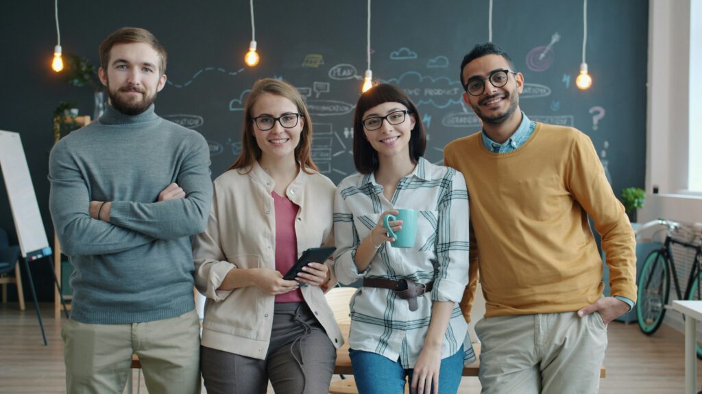 group of people standing in front of a chalk board smiling.