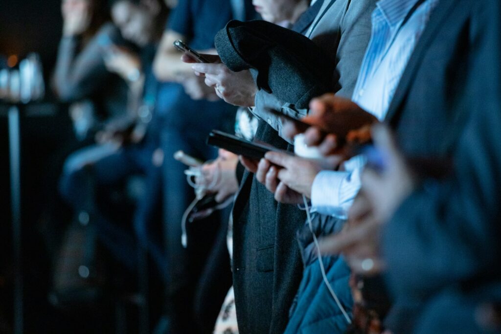 an out of focus frame showing a group of people in a line on their phones