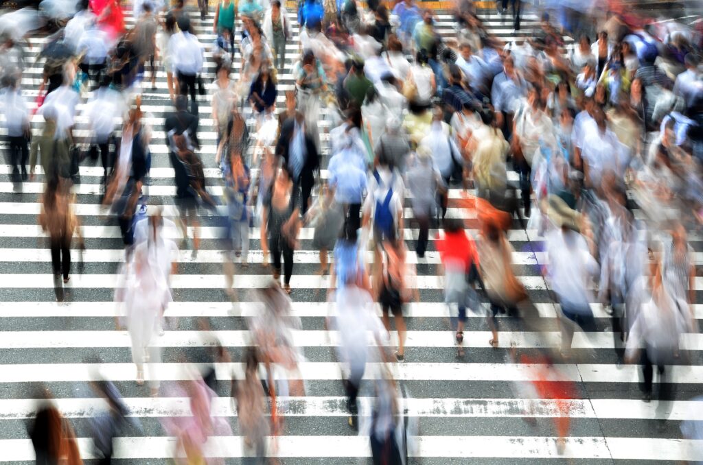 A blurred image of many people crossing a crosswalk.
