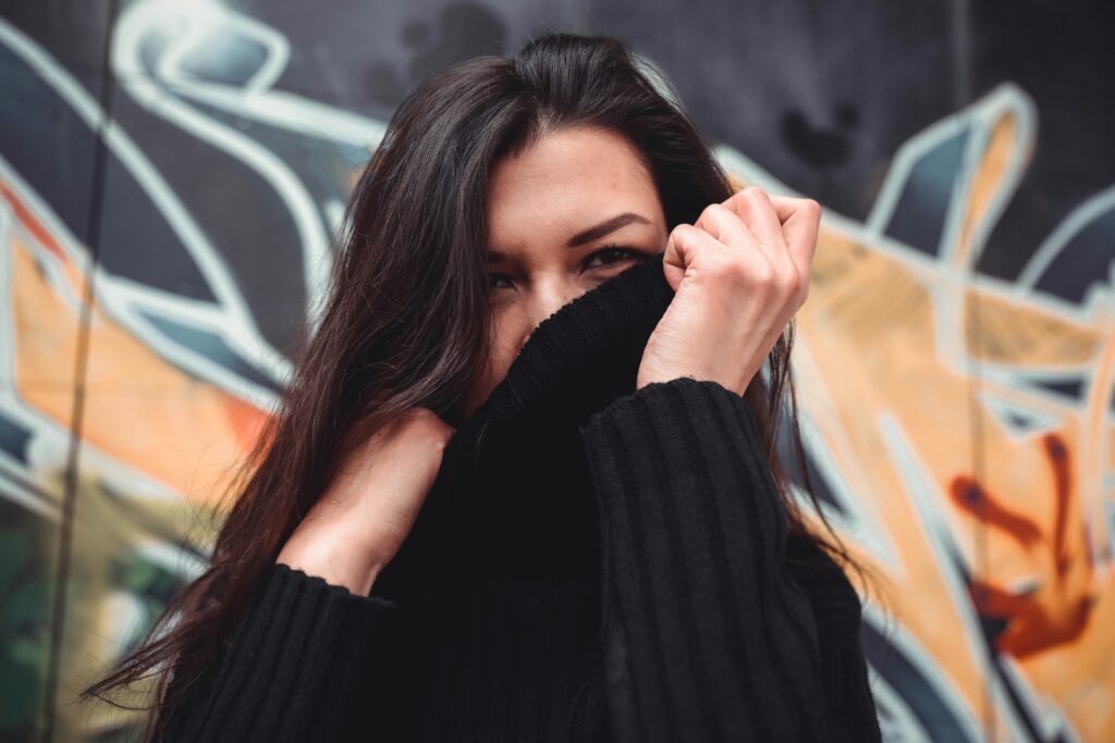 A woman hides part of her face with her sweater