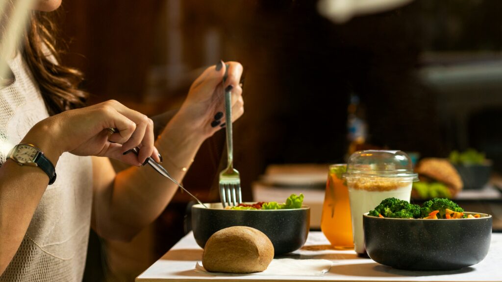 a woman holding a knife and fork and is about to start eating a bowl of food