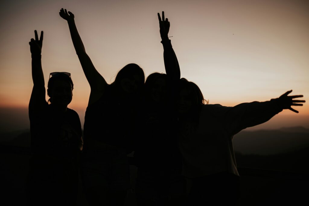 a group of silouhetted people jumps up in the air