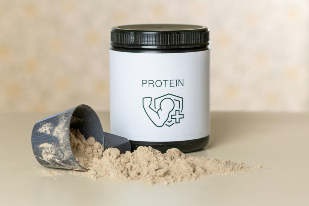 A jar of protein powder next to a scoop of powder