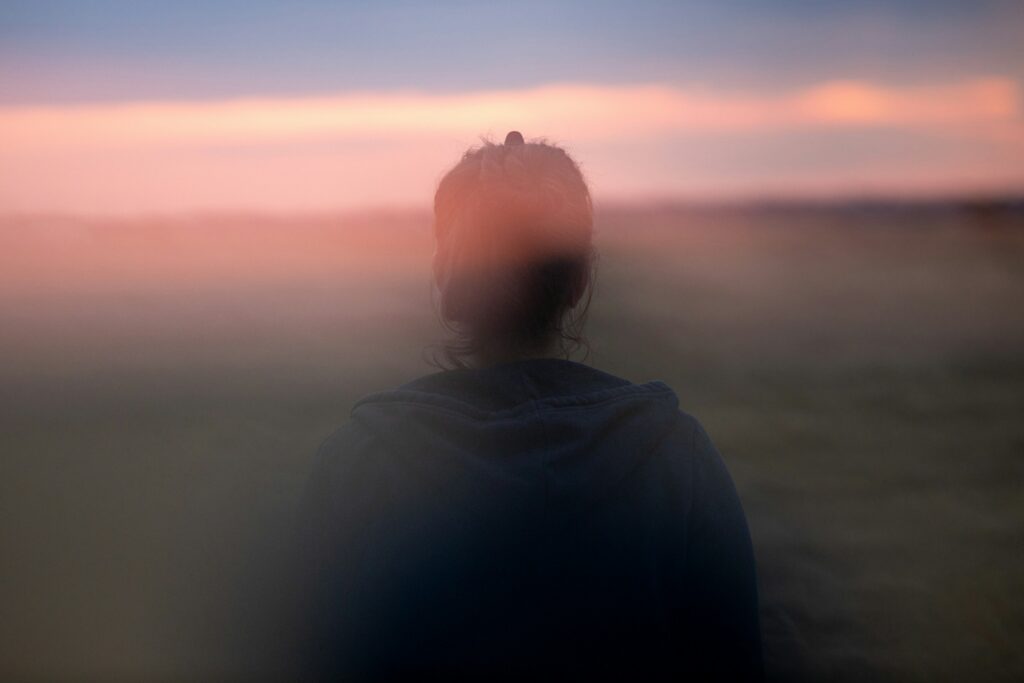 A blurred figure looking out toward the horizon at dusk